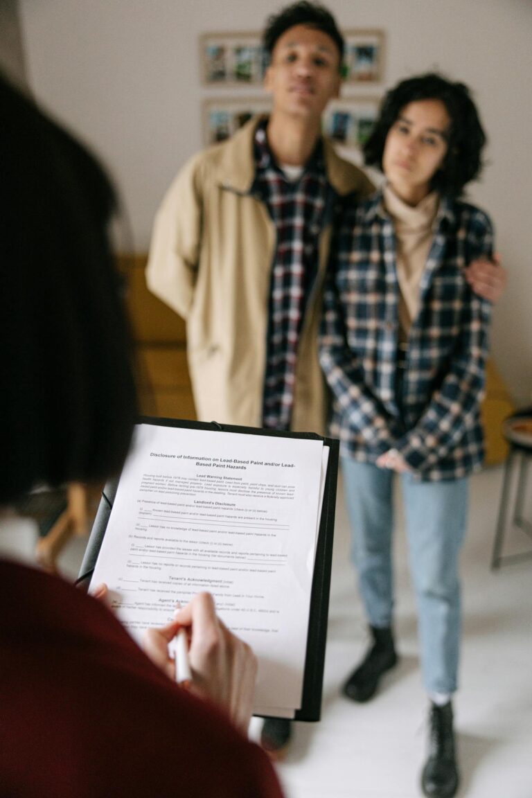 A focused view of a couple discussing a tenancy document with an agent in an rental home setting.