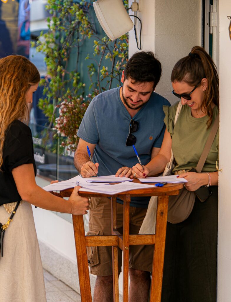 三个年轻人在外面的桌子上签署文件。.