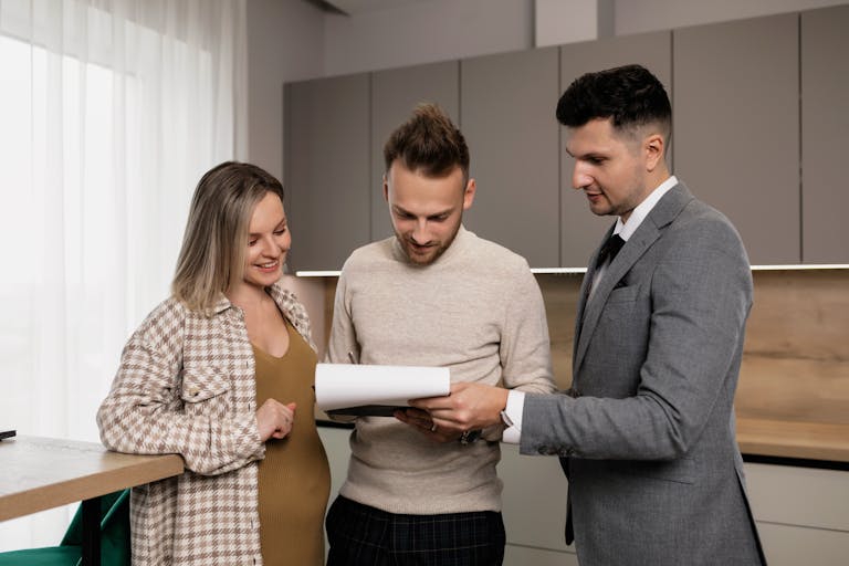 An agent presents a property management contract to a young couple in a modern indoor setting, discussing details of Auckland Property ROI.