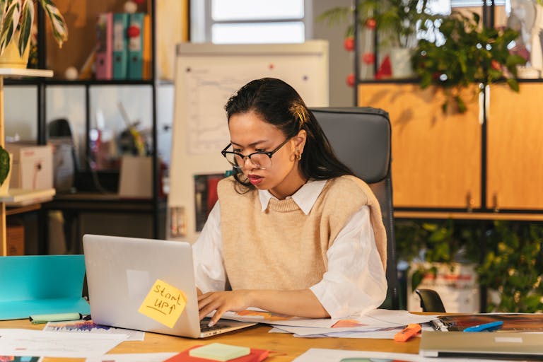 A female property manager with glasses concentrating on laptop work in an office.