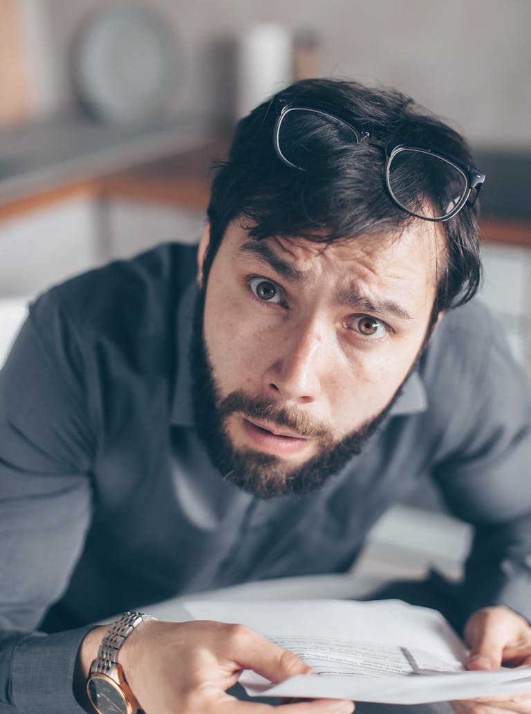 Portrait of an astonished man with a beard holding a rent arrears statement.