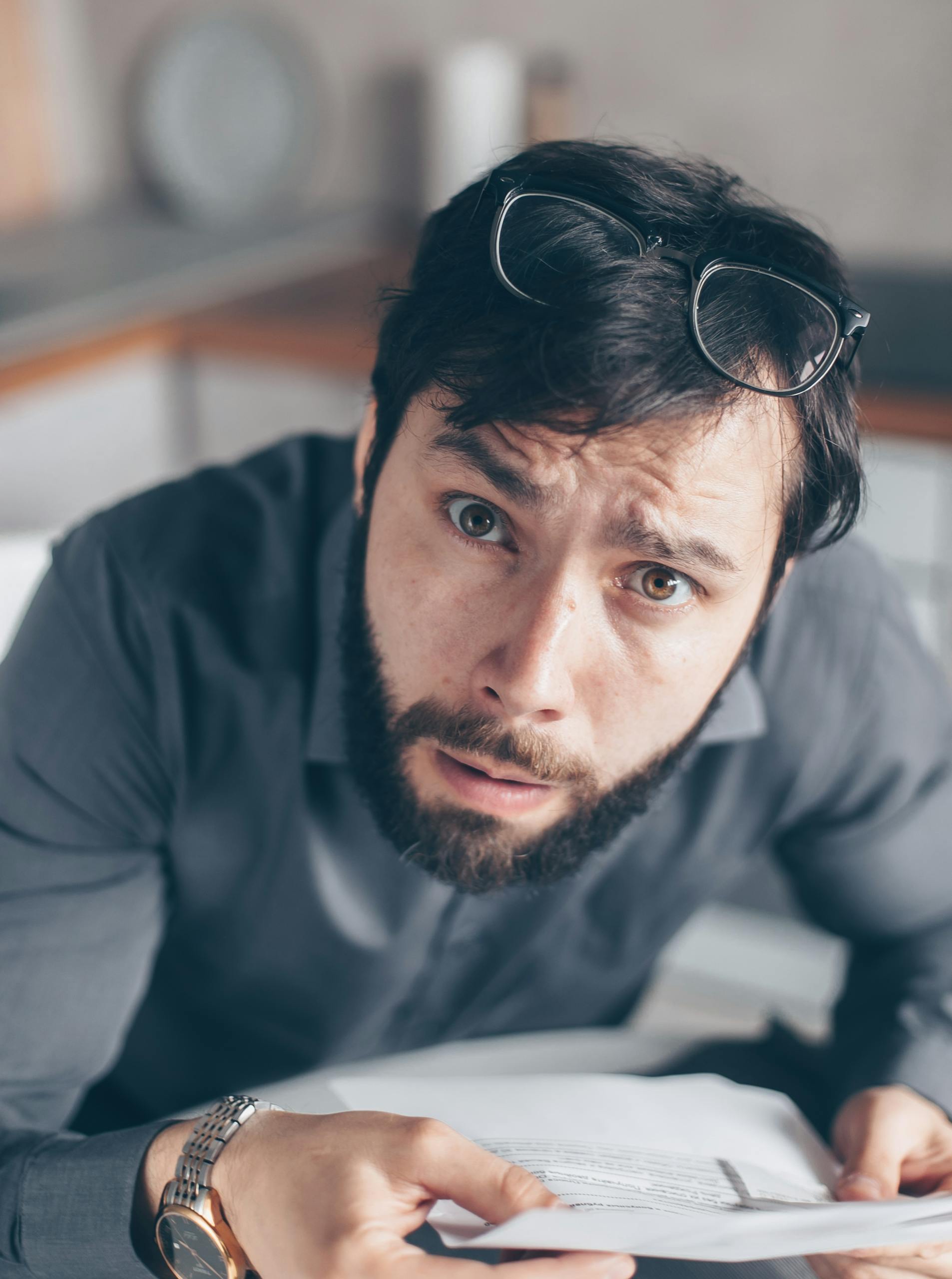 Portrait of an astonished man with a beard holding a rent arrears statement.