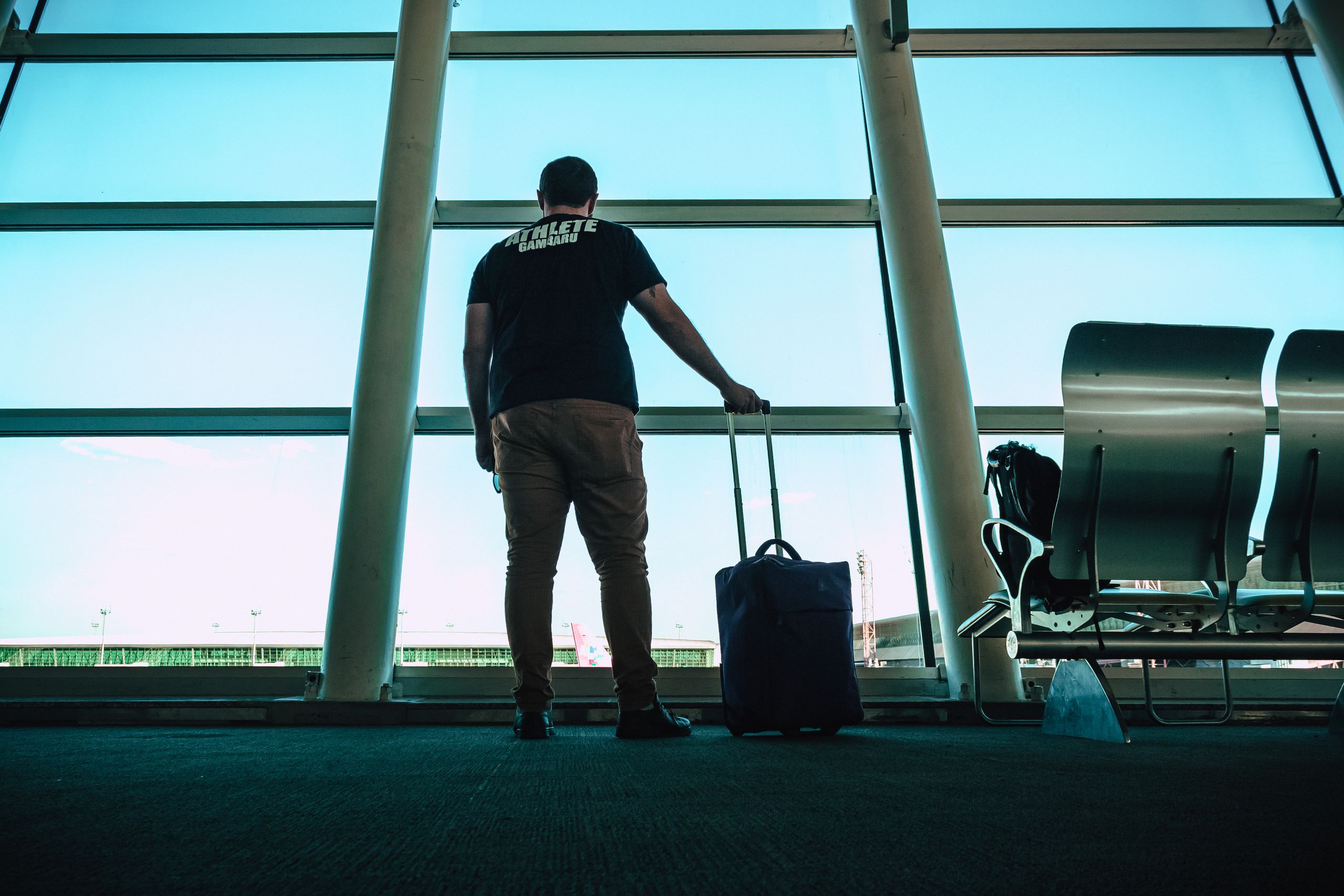 Man with luggage waiting at airport, signifying landlords leaving the country.