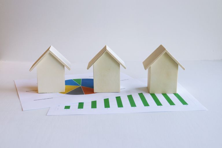 Wooden model houses on graphs depict real rental market analysis and trends. How much rent to charge being the question that comes to mind.