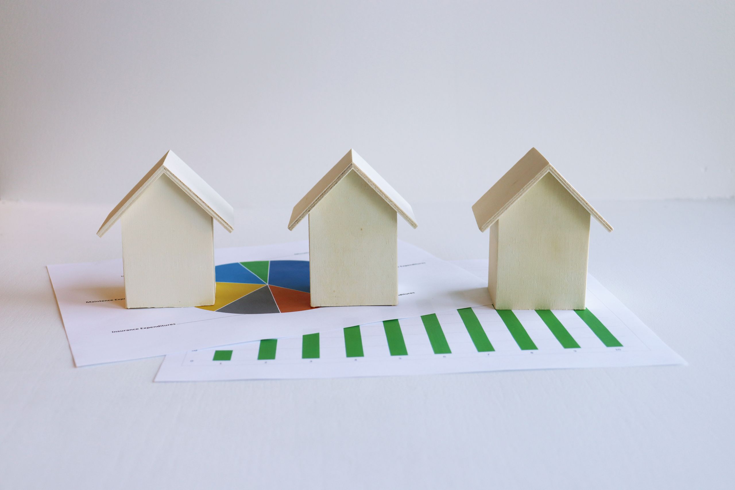 Wooden model houses on graphs depict real rental market analysis and trends. How much rent to charge being the question that comes to mind.